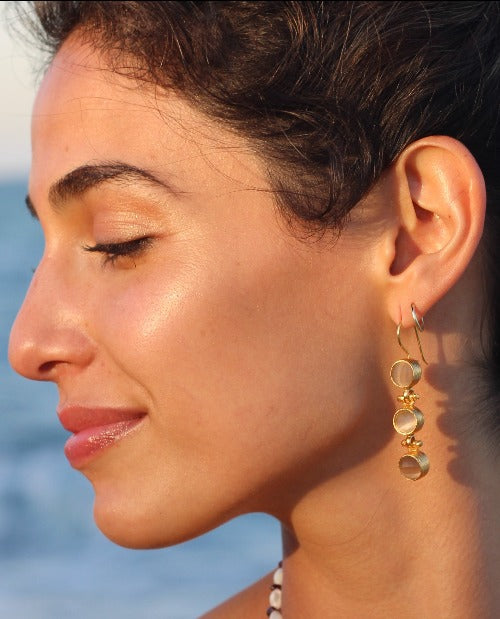 Pendientes summer triology puestos en una oreja, pendientes bañados en oro